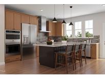Well-lit kitchen with stainless steel appliances, wood cabinets, island with seating and modern pendant lighting at 1038 Zelkova Ln, Chapel Hill, NC 27517