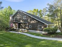 Two-story home showcasing a unique wood facade, balcony, and a stone chimney at 13 Crosswinds Estates Dr, Pittsboro, NC 27312