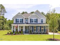 Charming two-story home featuring stone accents, gray siding, a manicured lawn, and beautiful landscaping at 1412 Main St, Lillington, NC 27546