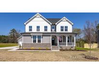 Charming two-story home featuring a welcoming front porch, brick accents, and a well-manicured lawn at 1412 Main St, Lillington, NC 27546