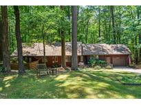 Charming home with a manicured lawn, mature trees, a wooden bench, and an attached two-car garage at 1608 New Hill Olive Chapel Rd, Apex, NC 27502