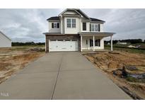 Two-story home features stone accents, white siding, a welcoming front porch, and a spacious driveway at 162 Tuskeegee Dr, Smithfield, NC 27577