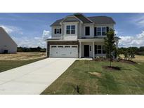 Charming two-story home with a two-car garage, stone accents, and a well-manicured lawn at 162 Tuskeegee Dr, Smithfield, NC 27577