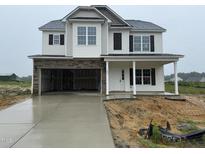 Two-story home with stone accents, a two-car garage, and a welcoming front porch at 162 Tuskeegee Dr, Smithfield, NC 27577
