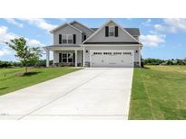 Charming two-story home featuring a gray exterior, attached garage, and a well manicured lawn at 188 Tuskeegee Dr, Smithfield, NC 27577