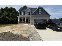 Beautiful two-story home featuring gray siding, stone accents, covered porch and two-car garage on a sunny day at 202 Tuskeegee Dr, Smithfield, NC 27577