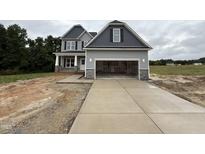 Two-story home with gray siding, stone accents, an attached garage, and a long concrete driveway at 202 Tuskeegee Dr, Smithfield, NC 27577
