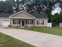 Charming single-story home with a well-manicured lawn and inviting front porch and long concrete driveway at 31 Kevior Ave, Four Oaks, NC 27524