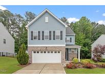 Charming two-story home featuring a brick-accented garage and a beautifully landscaped front yard at 320 Everly Mist Way, Wake Forest, NC 27587
