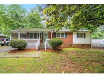 Charming brick home with a welcoming porch, complemented by lush greenery and a well-maintained yard at 407 W Sixth St, Siler City, NC 27344