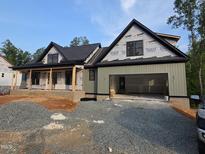 An exterior view of a home's facade featuring a two-car garage, porch and gray gravel driveway against a blue sky at 4248 Jacks Creek Trl, Burlington, NC 27215