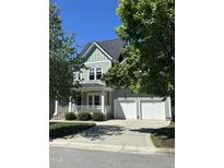 Charming two-story home with a three-car garage, inviting front porch, and manicured landscaping at 436 Edgepine Dr, Holly Springs, NC 27540