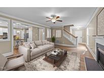 Inviting living room featuring a modern sofa, stylish rug, and an open layout to the kitchen and stairway at 436 Edgepine Dr, Holly Springs, NC 27540