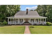 Charming home with a sprawling front porch, brick walkway, chimney, and lush landscaping at 5308 Stableview Ct, Holly Springs, NC 27540
