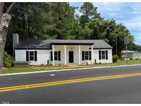 Charming single-story home featuring a covered front porch, black shutters, and fresh landscaping at 65 Prospect Church Rd, Erwin, NC 28339