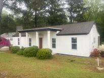 Charming single-story home features a welcoming porch, tidy landscaping, and updated white siding at 65 Prospect Church Rd, Erwin, NC 28339