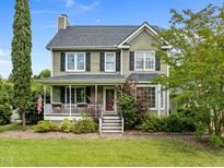 Charming two-story home featuring a welcoming front porch with black shutters and lush landscaping at 7621 Troy Stone Dr, Fuquay Varina, NC 27526