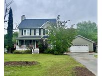 Charming two-story home with a covered porch, manicured lawn, and attached two-car garage at 7621 Troy Stone Dr, Fuquay Varina, NC 27526