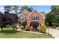 Beautiful brick home with manicured lawn, lush landscaping, and a charming walkway at 1004 Taywood Way, Apex, NC 27502