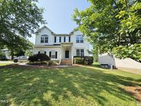 Charming two-story home featuring a manicured lawn, mature trees, and a welcoming front entrance at 1039 Bellenden Dr, Durham, NC 27713