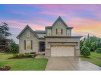 Charming two-story home with stone and siding exterior, landscaped lawn and two-car garage at 1201 Pleasant Falls Ct, Wake Forest, NC 27587