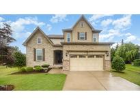 Charming two-story home with stone and siding details, lush lawn, and a two-car garage at 1201 Pleasant Falls Ct, Wake Forest, NC 27587