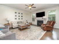 Comfortable living room with hardwood floors, a ceiling fan, a fireplace, and neutral paint at 1201 Pleasant Falls Ct, Wake Forest, NC 27587