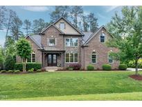 Beautiful brick home featuring manicured landscaping, a stone facade, and a covered front entrance at 1540 Sandybrook Ln, Wake Forest, NC 27587