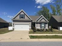 Charming single Gathering home features a two-car garage and neutral siding and manicured lawn at 233 Theys Mill Way, Fuquay Varina, NC 27526