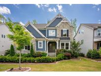 Beautiful two-story home featuring a stone facade, blue siding, and lush landscaping at 2737 Willow Rock Ln, Apex, NC 27523