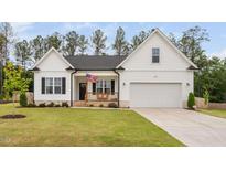 Charming single-Gathering home featuring an attached garage, a well manicured lawn, and a welcoming front porch with American flag at 297 Sexton Ln, Wendell, NC 27591