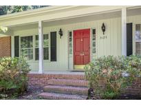 Charming home entrance featuring a bright red door with sidelights and classic black sconces at 3125 Stanford Dr, Durham, NC 27707