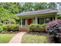 Charming single-story home featuring a welcoming red front door, lush landscaping, and brick pathway to the front porch at 3125 Stanford Dr, Durham, NC 27707