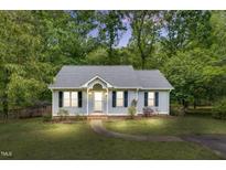 Charming single-story home featuring a well-manicured lawn, walkway, and inviting front porch, framed by lush trees at 324 Waterside Dr, Sanford, NC 27330