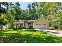 Charming yellow single-story home with a lush green lawn and mature trees at 3359 Denise St, Durham, NC 27704