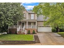 Charming two-story home with a welcoming front porch, brick accents, attached garage, and well-manicured landscaping at 6828 Edwell Ct, Raleigh, NC 27617