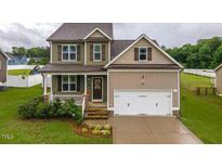 Charming two-story home featuring well-manicured lawn, inviting front porch, and attached two-car garage at 71 Sandy Farm Ct, Willow Springs, NC 27592