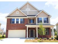 Charming two-story home with a brick and tan siding exterior, a well-manicured lawn, and an attached garage at 7584 Oakberry Dr, Raleigh, NC 27616