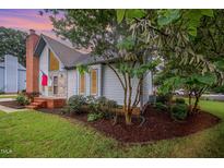 Charming home exterior features a brick chimney and nicely landscaped front yard at 100 Longneedle Ct, Raleigh, NC 27603