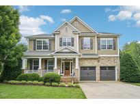 Inviting two-story home featuring a brick facade, manicured lawn, and attached two-car garage at 1008 Wolfs Bane Dr, Apex, NC 27539