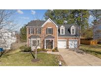 Charming brick home boasts a two-car garage, well-manicured lawn, and classic architectural details at 105 Stoney Dr, Durham, NC 27703