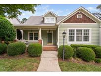 Charming green home featuring a cozy front porch and professionally landscaped front yard at 10516 Cokesbury Ln, Raleigh, NC 27614