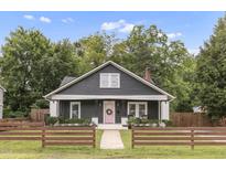 Charming home featuring a dark exterior with a pink front door and manicured front lawn at 106 E Delafield Ave, Durham, NC 27704