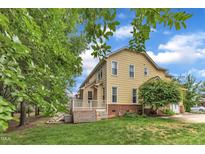 View of the rear exterior of the home featuring a deck, lush lawn, and mature trees at 11012 Southwalk Ln, Raleigh, NC 27614