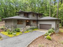 Modern home boasts meticulous landscaping and a gravel drive surrounded by a beautiful wooded area at 1115 Trailwood Dr, Raleigh, NC 27606