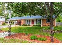 Charming single-story home with a red door, landscaped front yard, mature trees, and a covered carport at 1209 Maple Ave, Apex, NC 27502