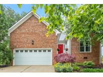 Beautiful brick home featuring an attached two-car garage, lovely landscaping, and a vibrant red front door at 123 Chimney Rise Dr, Cary, NC 27511