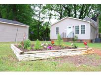Landscaped front yard with flower garden leading to the charming beige house with inviting front porch at 1536 Granville Street, Burlington, NC 27215