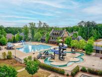 Aerial view of community pool and clubhouse with winding slide, perfect for outdoor fun and relaxation at 210 Mayfield Dr, Apex, NC 27539