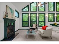 Sun-filled living room with fireplace and large windows showcasing the lush greenery outside at 224 Crawford Rd, Hillsborough, NC 27278
